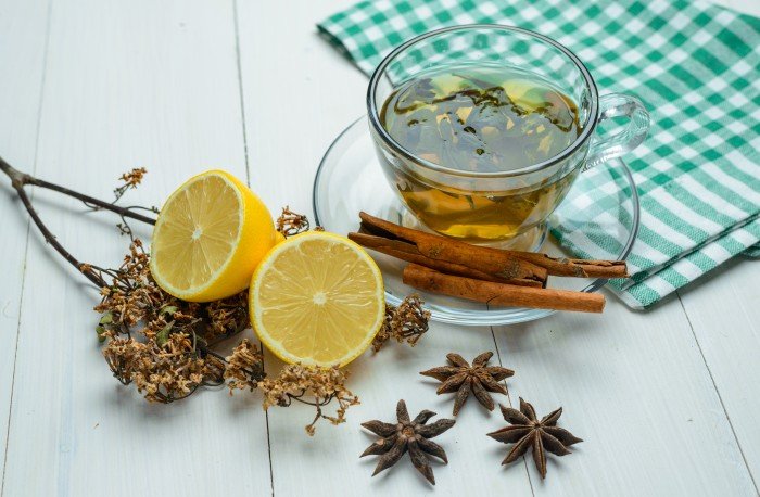 Jasmine infusion tea with lemon, cinnamon sticks, and star anise on a wooden table