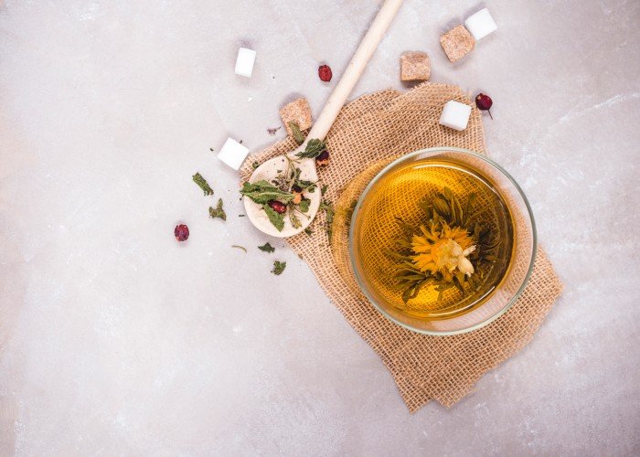 Antioxidant-rich chamomile infusion tea with dried flowers and herbs in a glass cup.