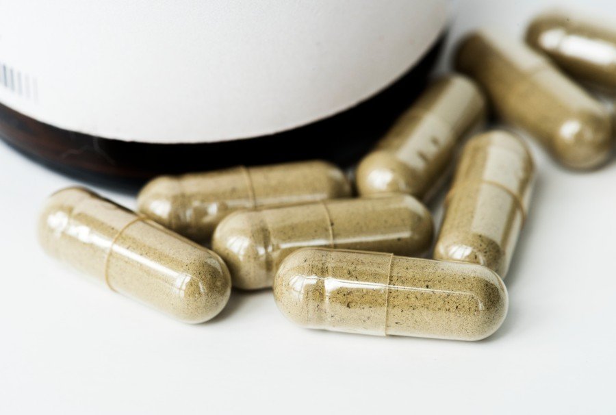 Ashwagandha capsules in a supplement bottle on a white background
